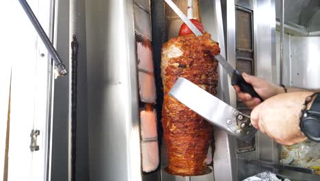 Fast-food,-a-man-slicing-grilled-chicken-and-beef-meat