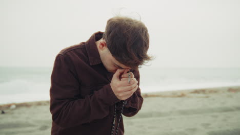 man crying while praying on the shore during winter