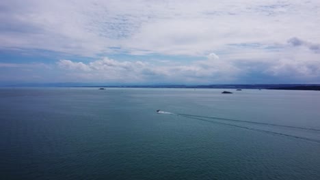 the video shows a large lake with a motorboat leaving a trail on the water. in the distance, islands and distant shores are visible, while clouds cover the sky.