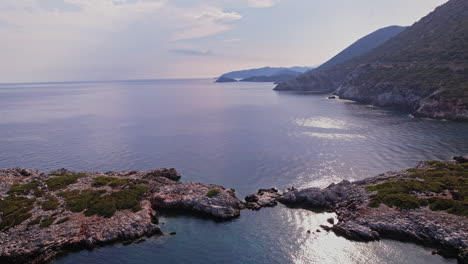 serene coastal view with rocky shores and distant mountains at sunset