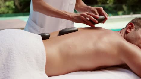 handsome man having hot stone massage