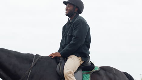 Teenager-Holding-Reins-And-Walking-While-Young-Man-Rides-Black-Horse-On-A-Track