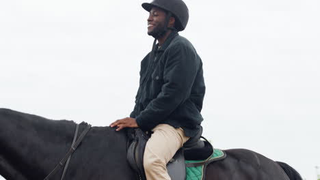 teenager holding reins and walking while young man rides black horse on a track