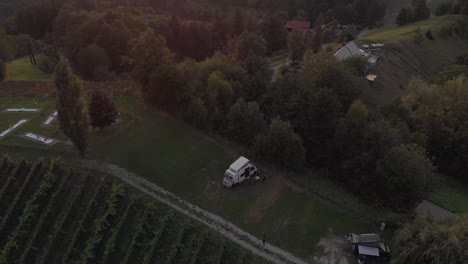 a-professional-looking-aerial-shot-of-a-camper-in-the-austrian-vineyards-and-alps-while-sunset