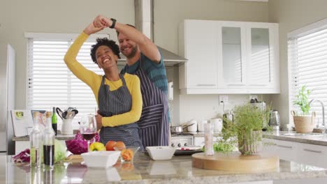 Video-De-Una-Feliz-Pareja-Diversa-Bailando-En-La-Cocina-Con-Delantales.