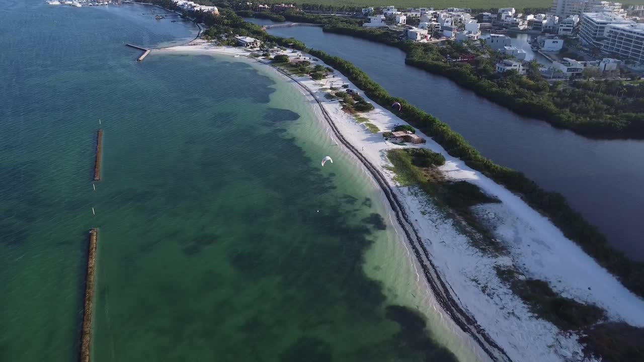 Aerial Drone View of Puerto Cancun beach with kite surfer over clear blue ocean waters