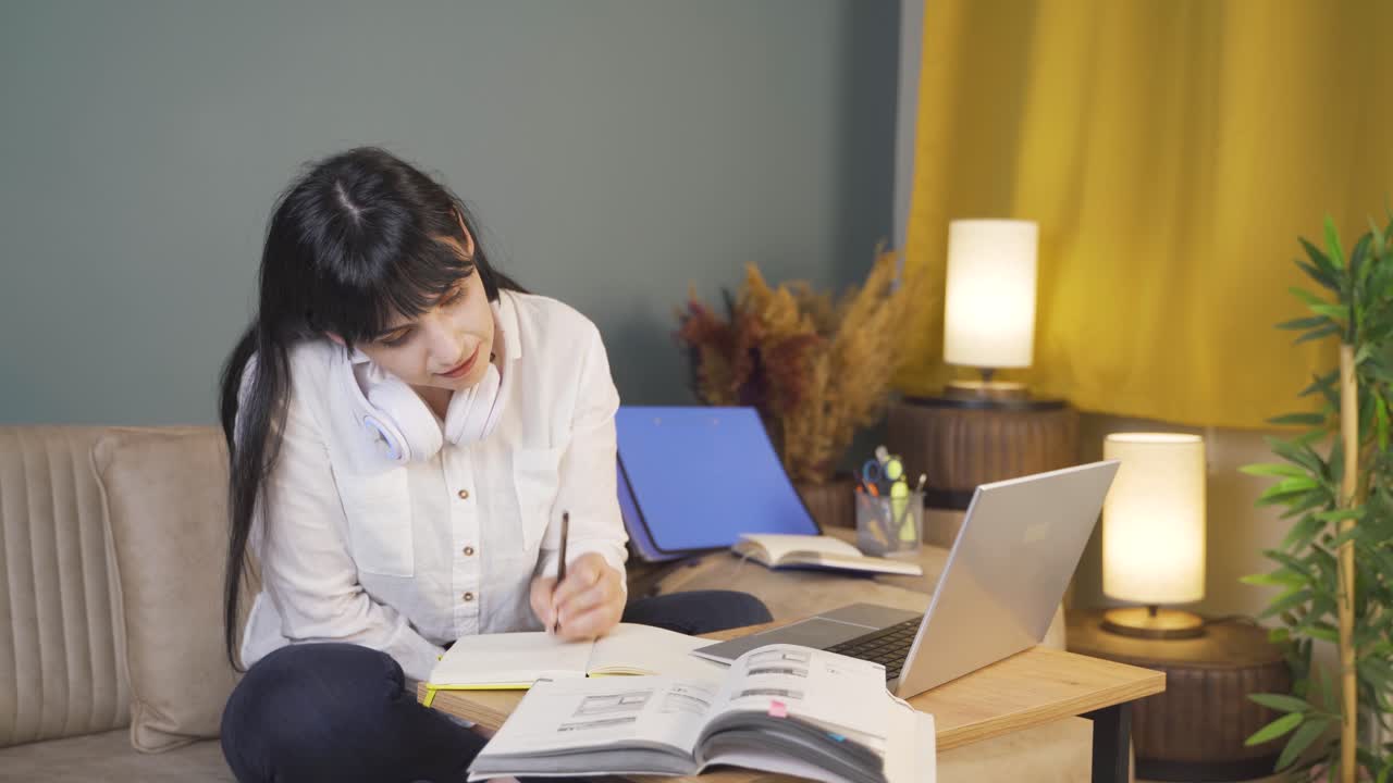 성공한 학생은 집에서 공부하는 동안 미소 짓고 카메라를 쳐다본다.