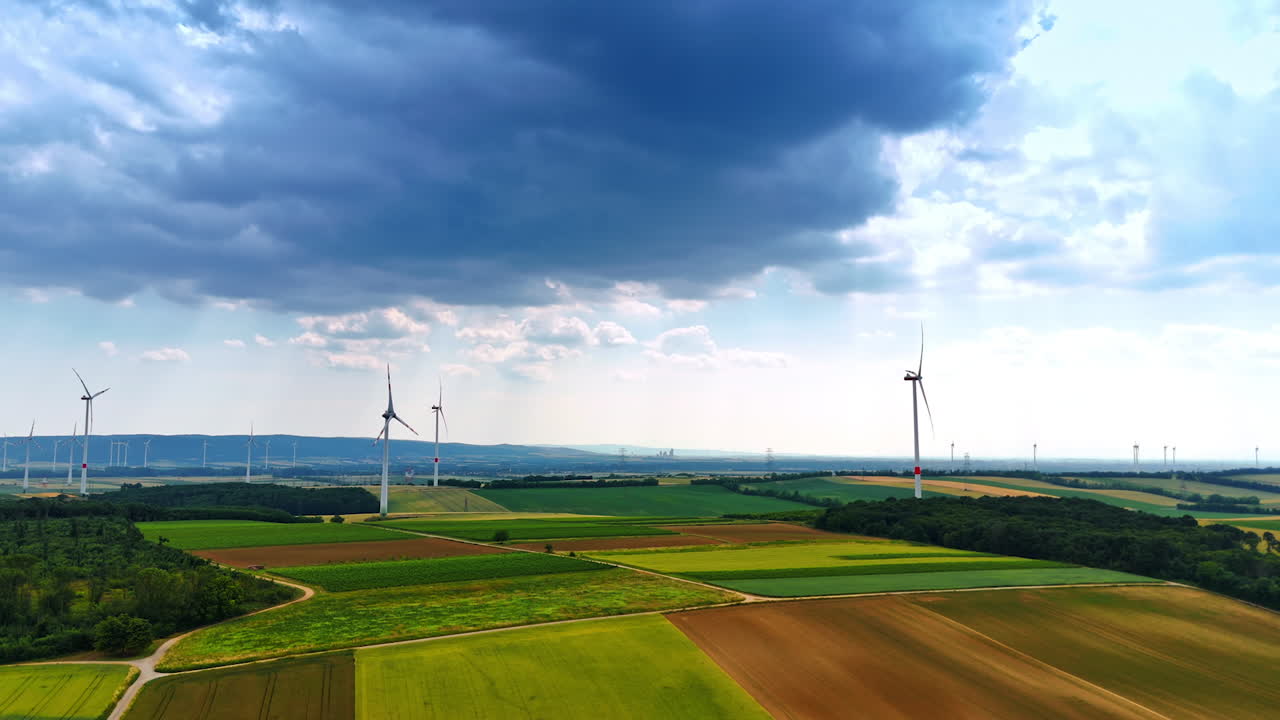 Beautiful agricultural fields used for energy production. Wind farms rotate in the wind producing green power