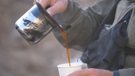 man pouring coffee into paper cup outdoors