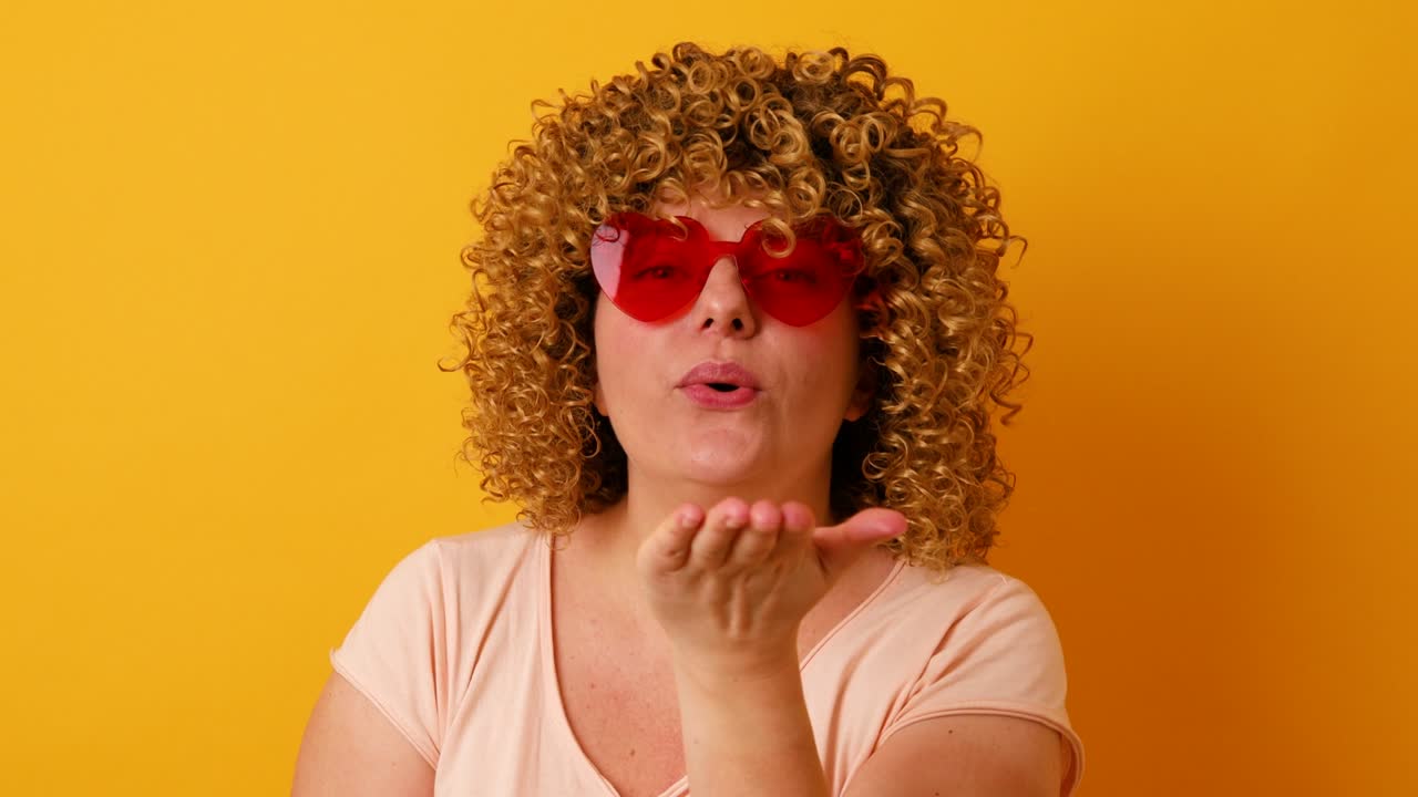 Cheerful 30s woman with afro hairstyle having fun on yellow background