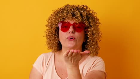 mujer alegre de 30 años con peinado afro divirtiéndose en un fondo amarillo