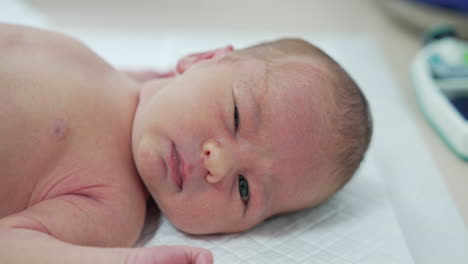 infant hiccups. newborn baby boy laying on hospital table. side portrait of a cute child. concept of hospital and happy motherhood.