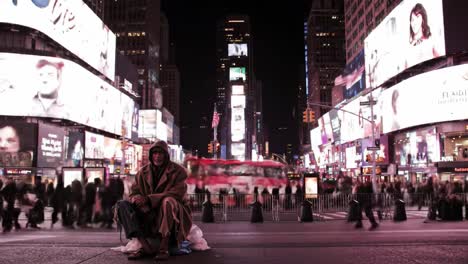 in the heart of times square at night, a homeless man sits calmly on the ground, surrounded by a vibrant crowd and illuminated billboards.