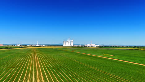 flying closer to a plant working in the rural area. approaching the industrial area with large pipes producing white smoke