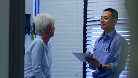 Young-Asian-male-doctor-and-senior-patient-interacting-with-each-other-at-clinic-4k