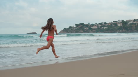 young woman running at coastline. carefree girl enjoying holiday at beach.