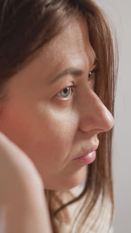 una mujer se limpia la cara con toner facial en el inodoro. una atractiva dama morena con túnica de peluche aplica toner hidratante en la cara en el baño en cámara lenta