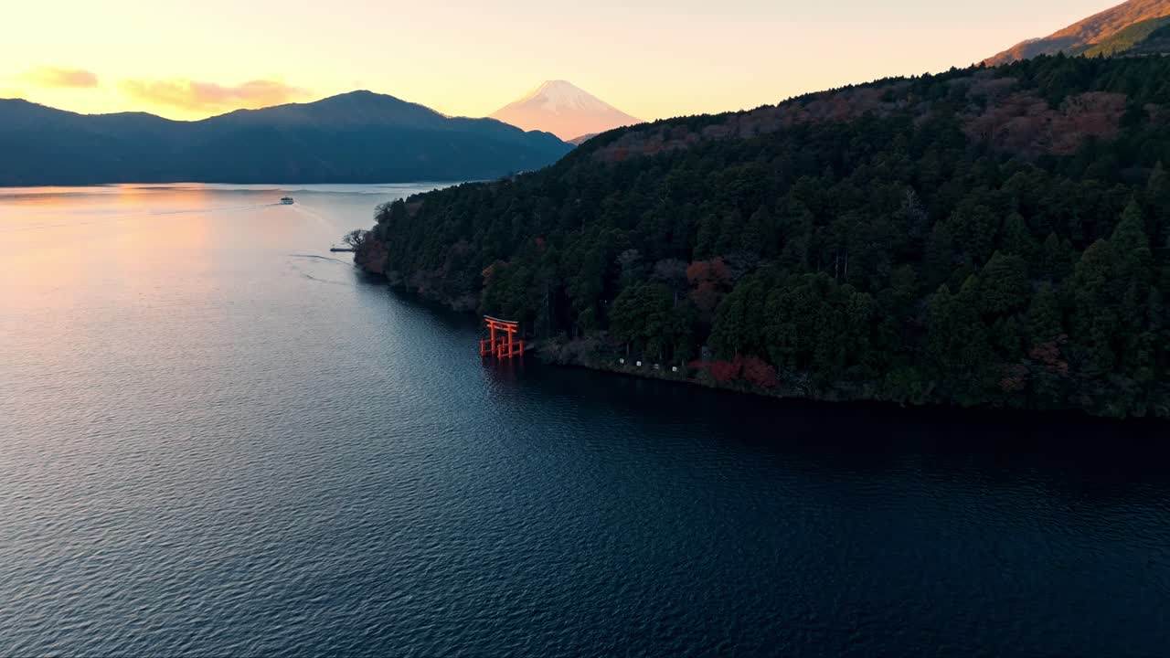 해가 지는 하코네 사원의 매혹적인 드론 촬영, 아시 호수의 조용한 물을 내려다보는 상징적인 빨간 토리 게이트를 특징으로합니다.