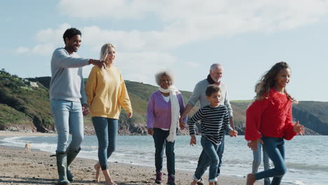 active multi-generation family with dog walking along autumn beach