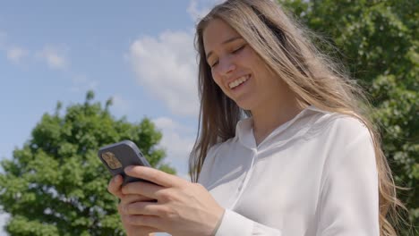 joven mujer de negocios caucásica mensajes de texto mientras sonríe, día soleado