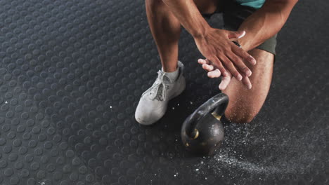lifting kettlebell, man clapping hands with chalk in gym workout session