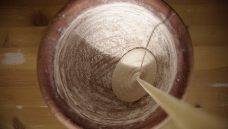 vertical - top down - sourdough starter is poured into the wooden mixing bowl