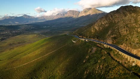 drone in crane motion above hermanus highway through lush rich hillside