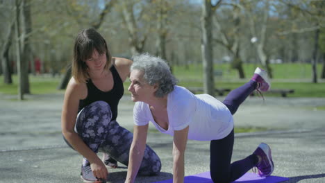 una mujer mayor sonriente con un joven entrenador durante el entrenamiento en el parque.