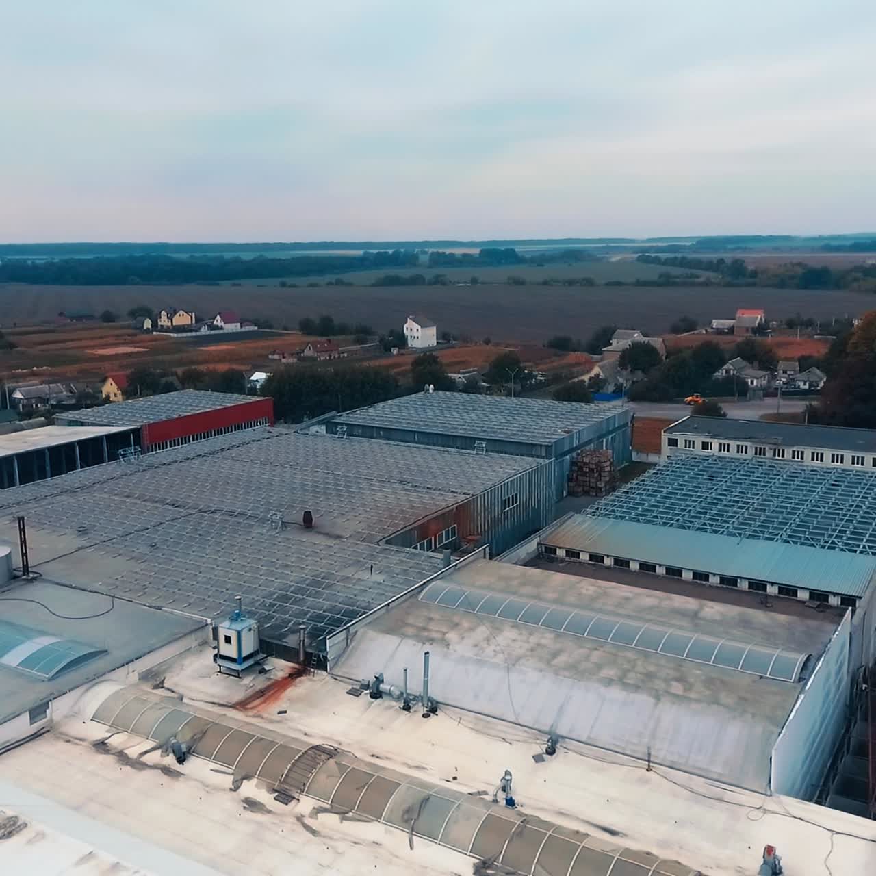 Suburban industrial area for building purposes. Flying around the hangars and tanks at the backdrop of village and farmlands. Drone footage