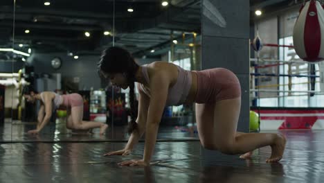 mujer asiática haciendo ejercicio gimnasio interior con espejo, chica en forma de fitness en ropa deportiva estirando el músculo
