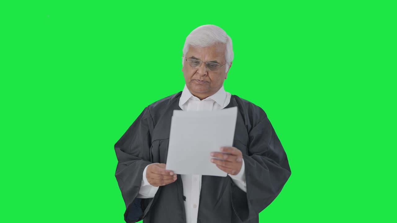 Avvocato senior indiano che legge le carte del tribunale su schermo verde