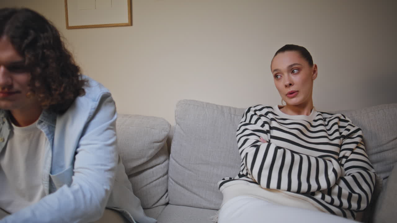 Primo piano di una coppia sposata in difficoltà che litiga sul divano di un appartamento. Donna preoccupata
