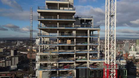 luftdrohnenflug um einen im bau befindlichen wolkenkratzer in deansgate mit nackten betonstrukturen und einem blick auf die umliegenden dächer der stadt im stadtzentrum von manchester