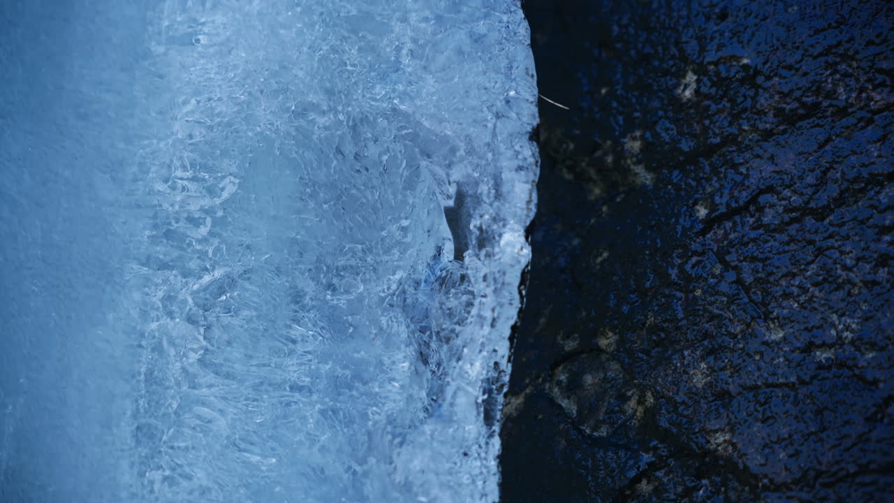 Close up of ice melting close to the rock and the water starts dripping down