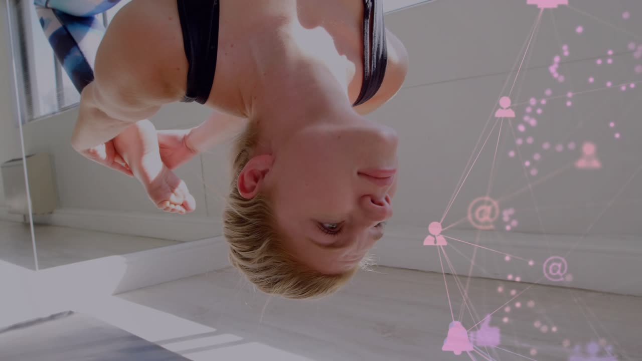 Woman holding inverted pose in yoga, hammock settling showing blue silk, pink overlay beside her