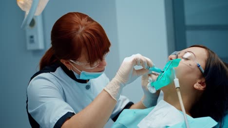 dental specialist treats woman's teeth in clinic. professional dentist makes injection into oral cavity to a patient in dental office.