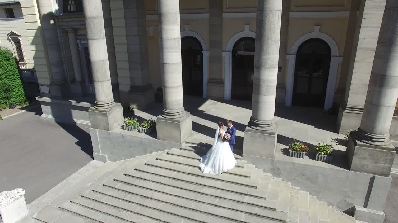 Elegant Wedding Couple Near The Old Building. Aerial shot of a wedding couple witn old building with columns on background