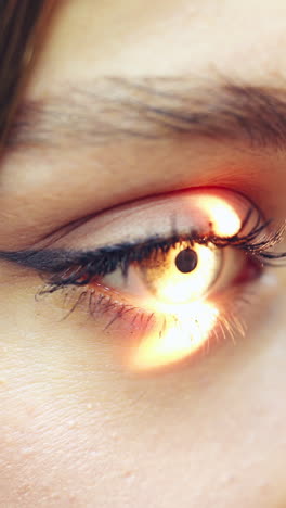 young female checking her eyes at a doctor. bright light shines inside the woman's eye. concept of eye and cornea care. close-up. vertical video