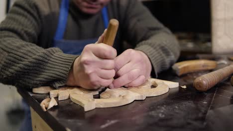 working days of a professional carpenter in a workshop, a craftsman at his workplace is planing a future furniture part with a planer. concentrated work with details