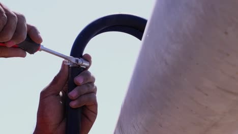 view of screwdriver being used to tighten hose clamp on pipe outside