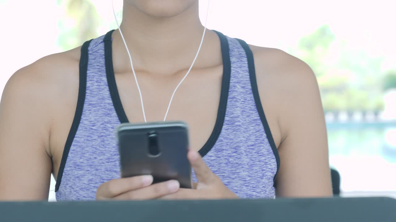 chica asiática corriendo en la cinta de correr en el gimnasio con auriculares