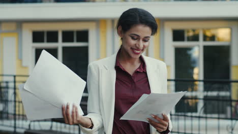 mujer de negocios sonriente leyendo un proyecto al aire libre. mujer de raza mixta diciendo wow