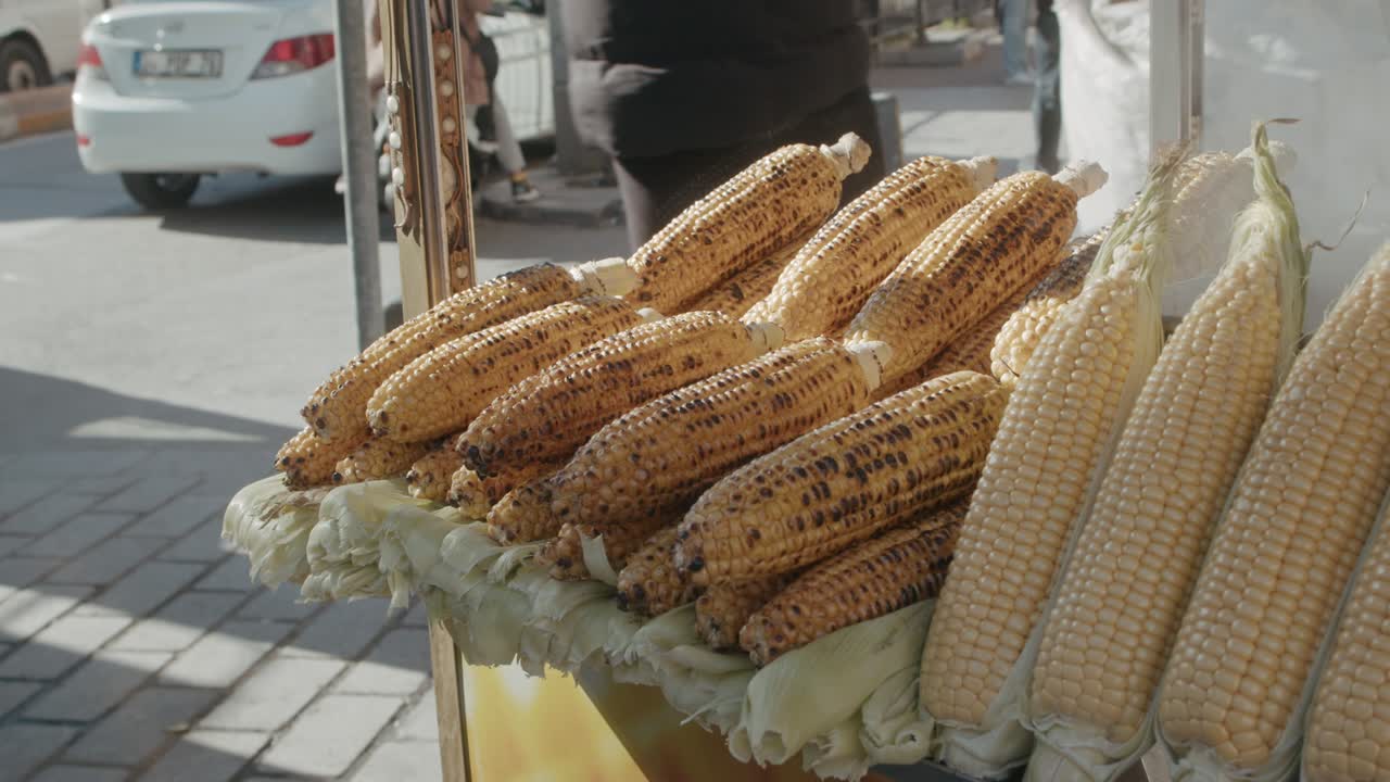 vendedor de comida callejera con deliciosos maíz amarillo a la parrilla, cocido y al vapor servido y listo para comer en el puesto