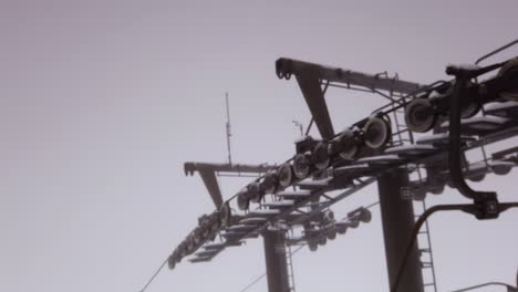 Mechanical-steel-ski-resort-chair-lift-pulley-system-rails-down-snowy-winter-mountain,-Poland