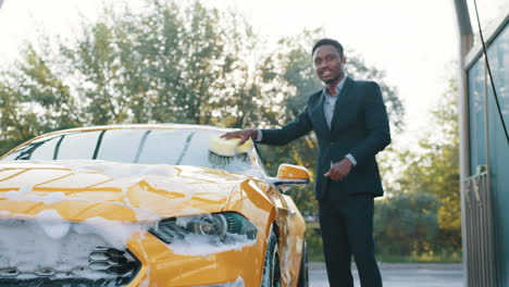 un hombre de negocios lavando su coche amarillo.