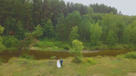 just-married-couple-near-river-against-forest-bird-eye-view