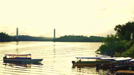 barco largo tradicional se desvía a la orilla junto a otros barcos largos atracados con el puente de brasil a guayana francesa en el fondo