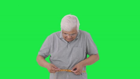 Happy-Indian-old-man-checking-his-waist-size-using-inch-tape-Green-screen