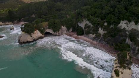 Aerial-view-of-cave-on-the-sandy-beach,-beautiful-and-wild-nature-scenery-of-New-Zealand