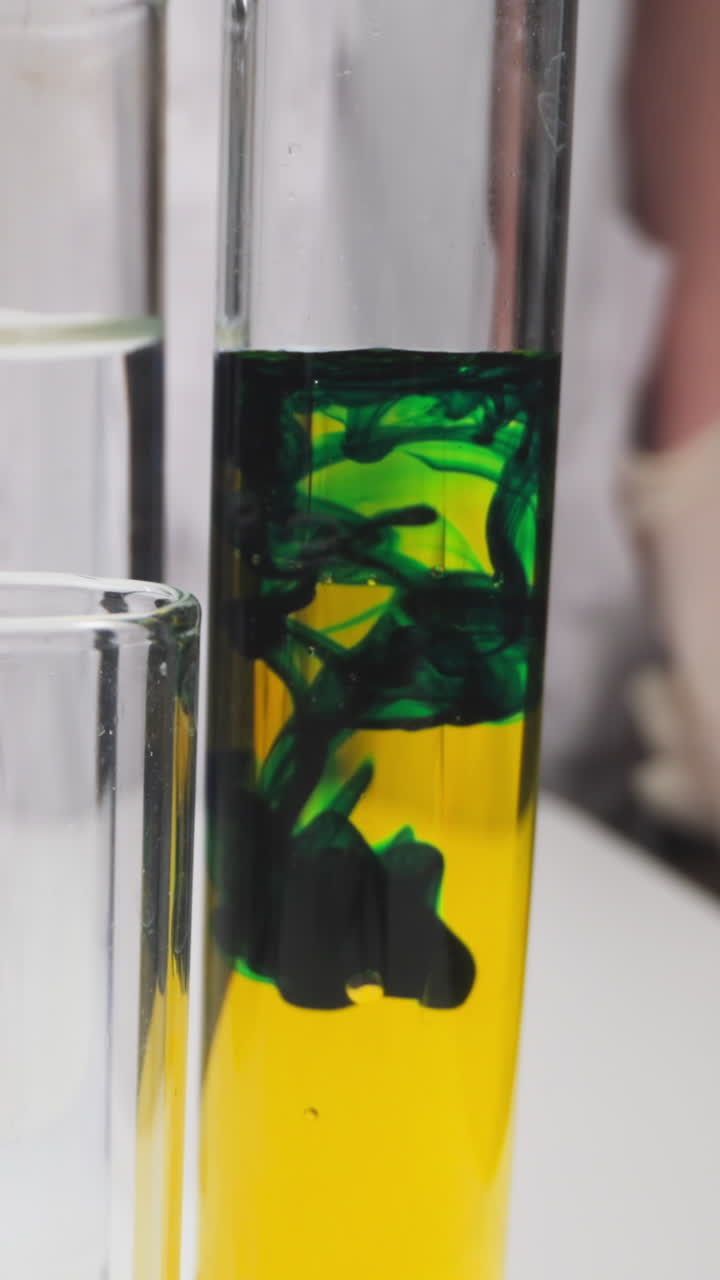 Chemists drips green reagent into test tube with yellow liquid in workshop slow motion. Probe lens shot of scientific investigation closeup